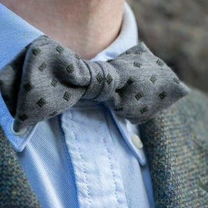 A close up of a Man wearing the Grey Marle with Olive Diamond Bow Tie with a Blue Button Down Shirt and Grey Woven Blazer. 