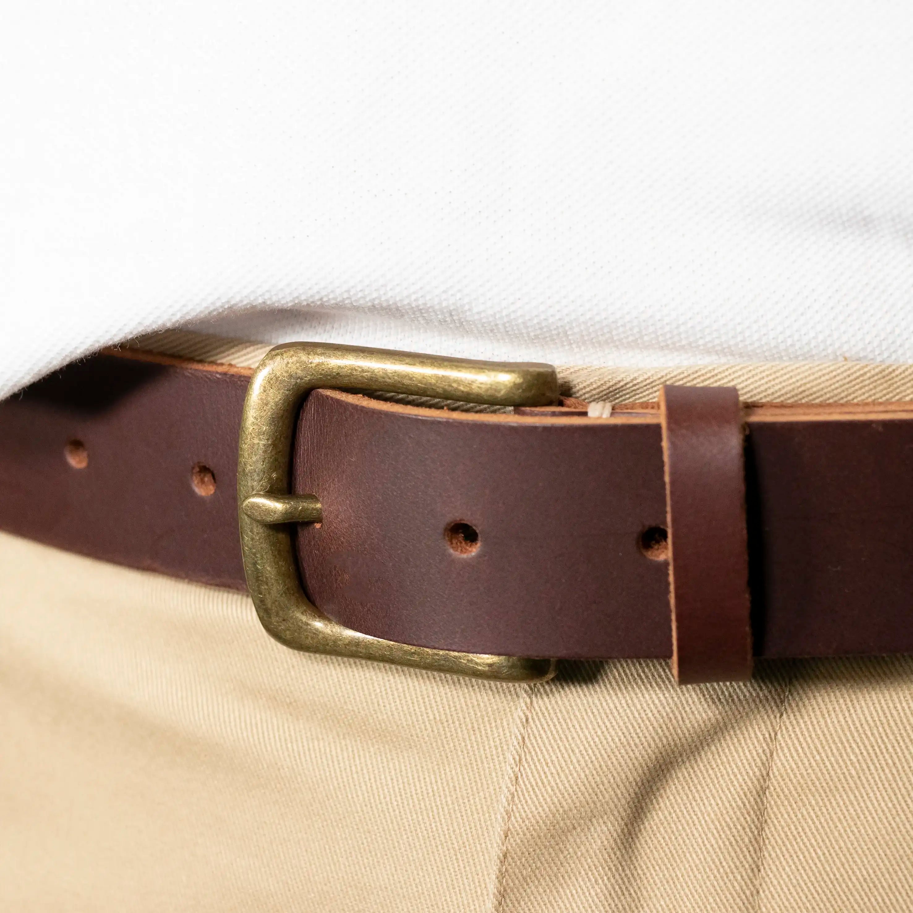 A close up of the Brown Everyday Classic Leather Belt and its Brass Hardware worn with Tan Trousers and a White Shirt. 