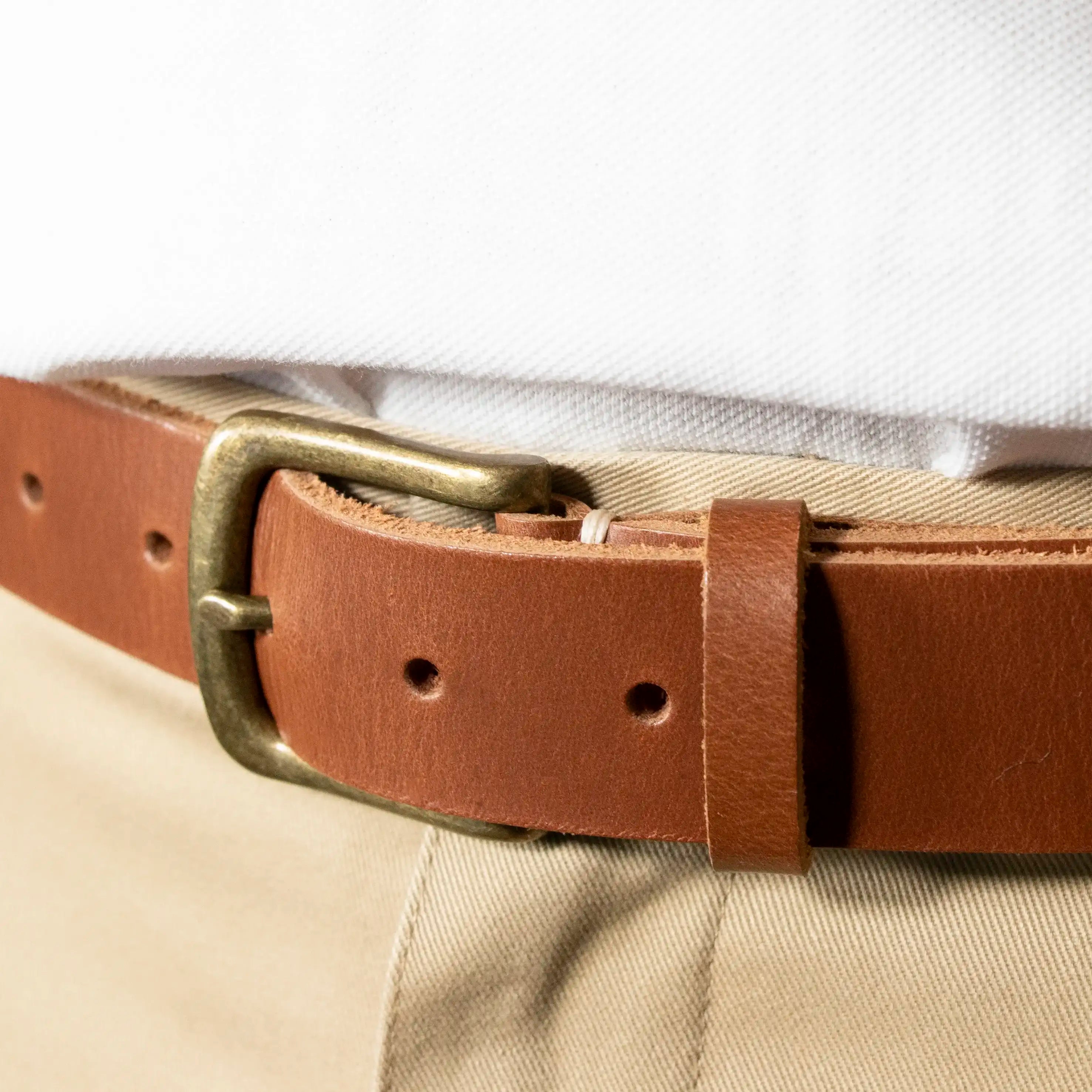 A close up of the Tan Everyday Classic Leather Belt with Brass Hardware worn with Tan Trousers and a White Shirt.