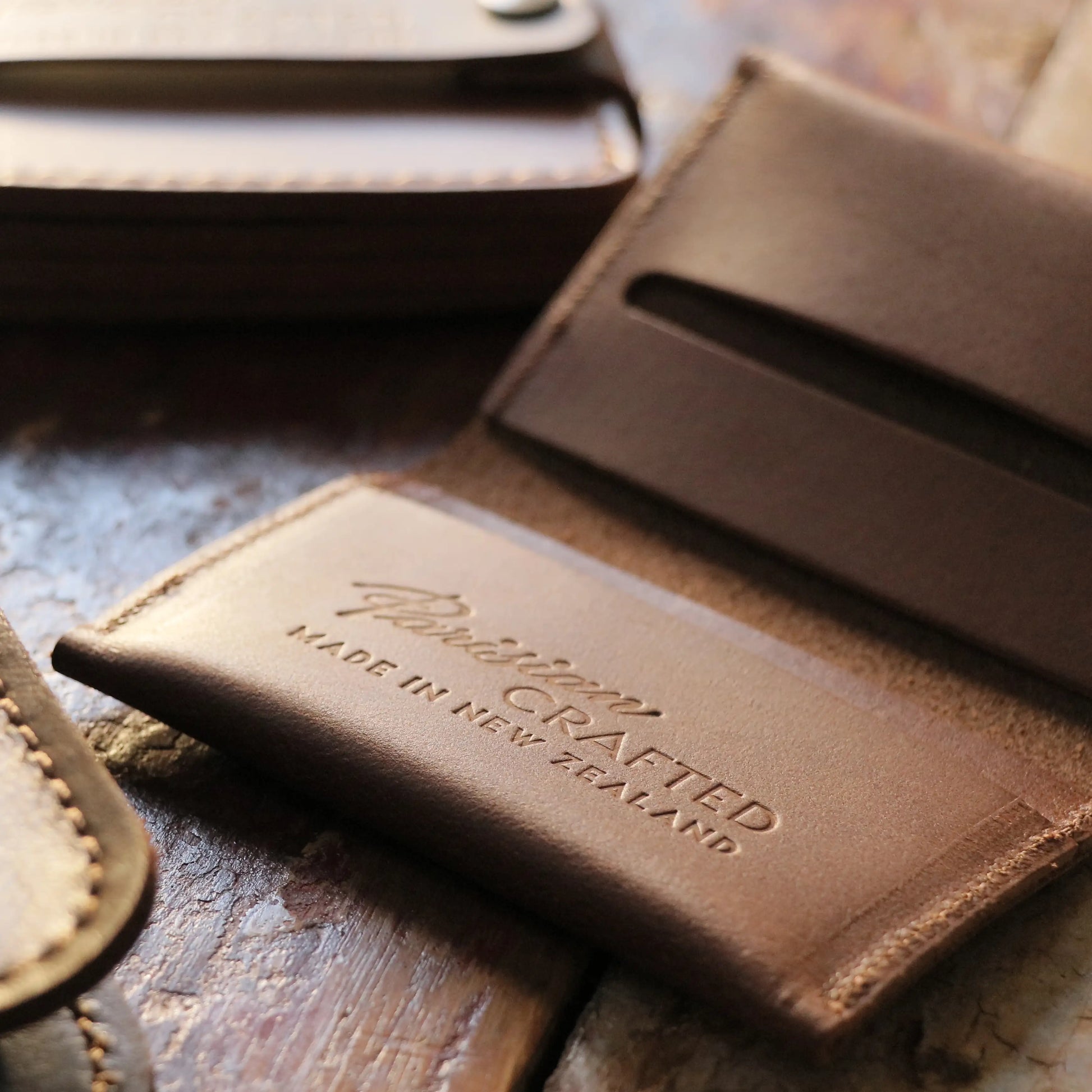 A close up of the embossed text 'Parisian Crafted Made in New Zealand' on the inside of a Tan Leather Folded Card Wallet.