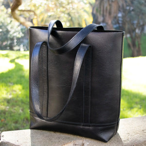 The Black Everyday Leather Tote sitting outdoors.