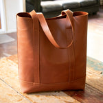 The Tan Everyday Leather Tote sitting on a wooden table in the sun.