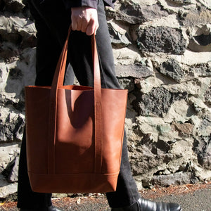 A close up of a Man carrying the Tan Everyday Leather Tote in the sun.