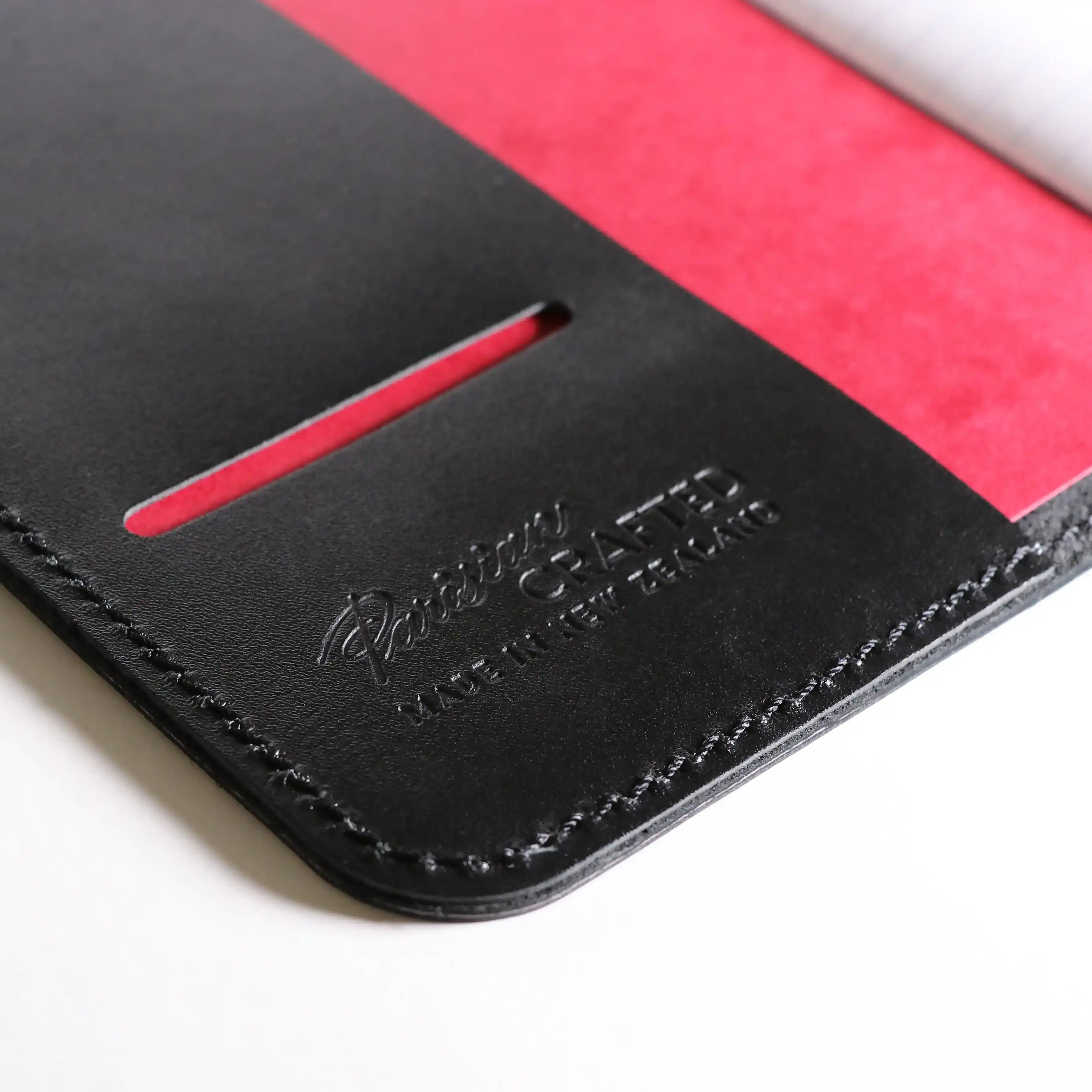 A close up of the inside of the Black Leather Notebook showing the embossed Parisian branding and the Red front page of the notebook inside.