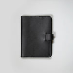 The Black Leather Notebook sitting closed on a white background.