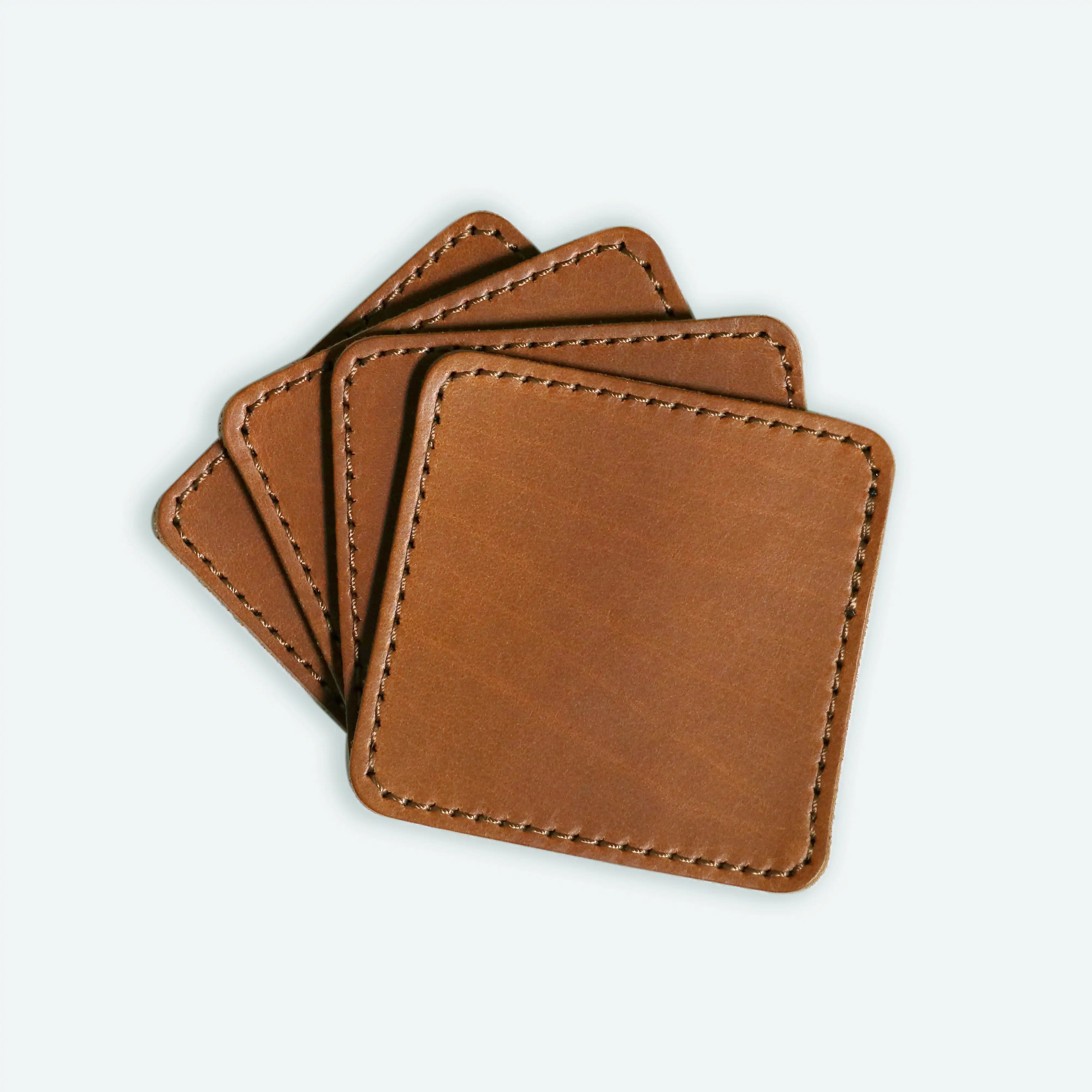 The set of four Stitched Leather Coaster Set sitting on top of each other splayed out a white background.